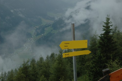 Wegweiser von der Kaserstatt-Alm nach Fulpmes, Nieders und Neustift. Im Hintergrund das Stubaital.